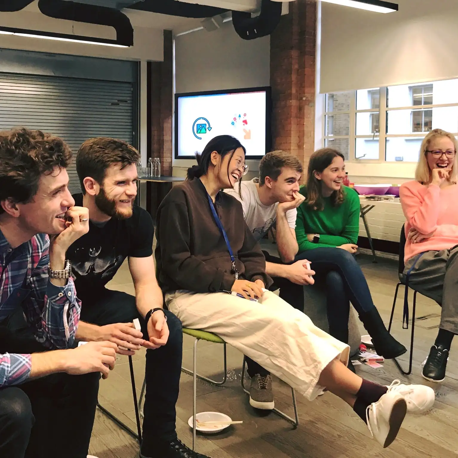 Photo of colleagues laughing and smiling while listening to a presentation.