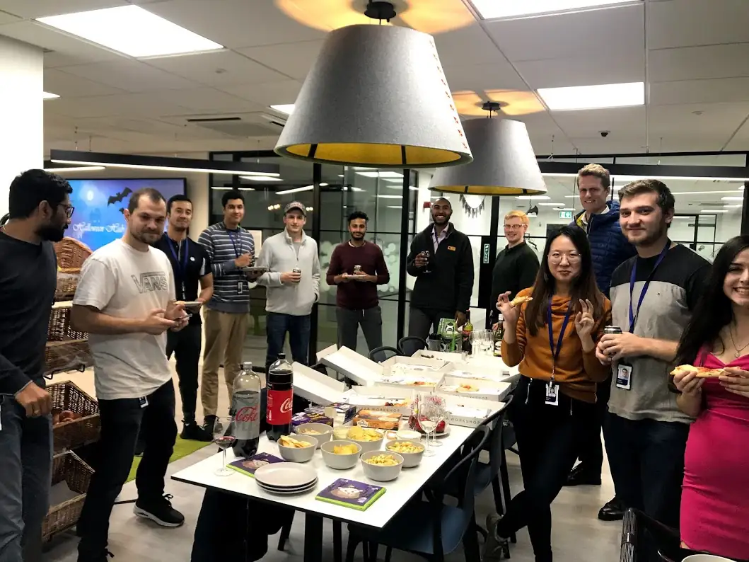 Photo of colleagues enjoying pizza, snacks, and soft drinks in the Bristol office
